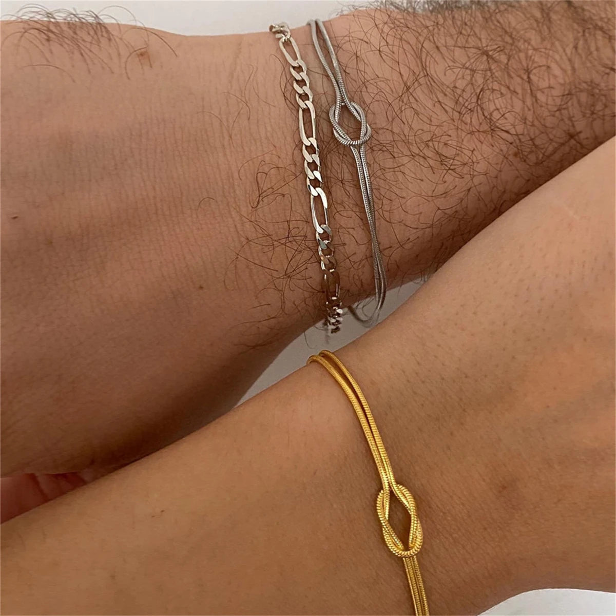 Bracelet chaîne serpent bicolore – homme portant un bracelet chaine serpent avec noeud en argent et femme portant le même bracelet mais couleur doré
