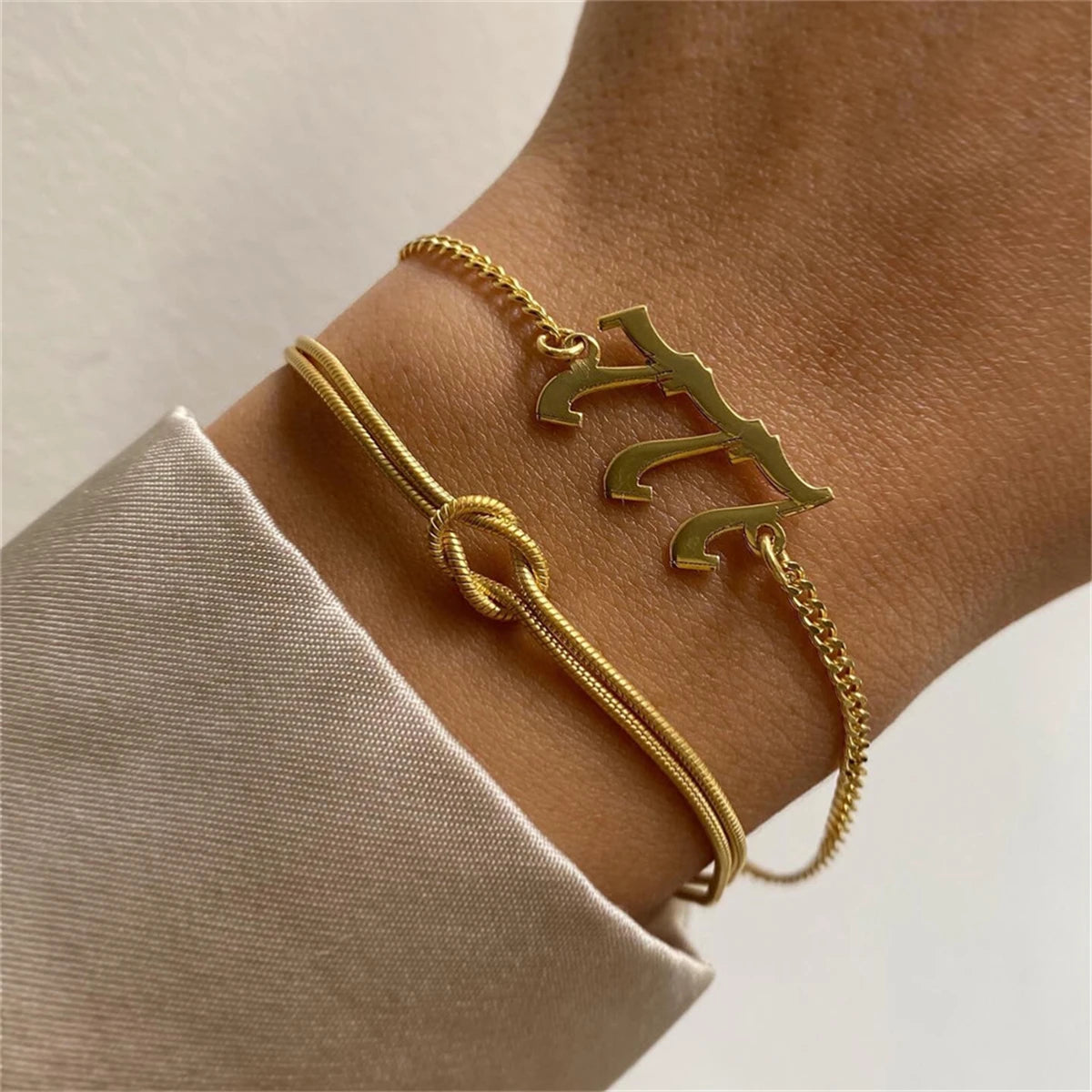 Bracelet doré en chaine serpend et noeud au centre, porté par une femme – style élégant