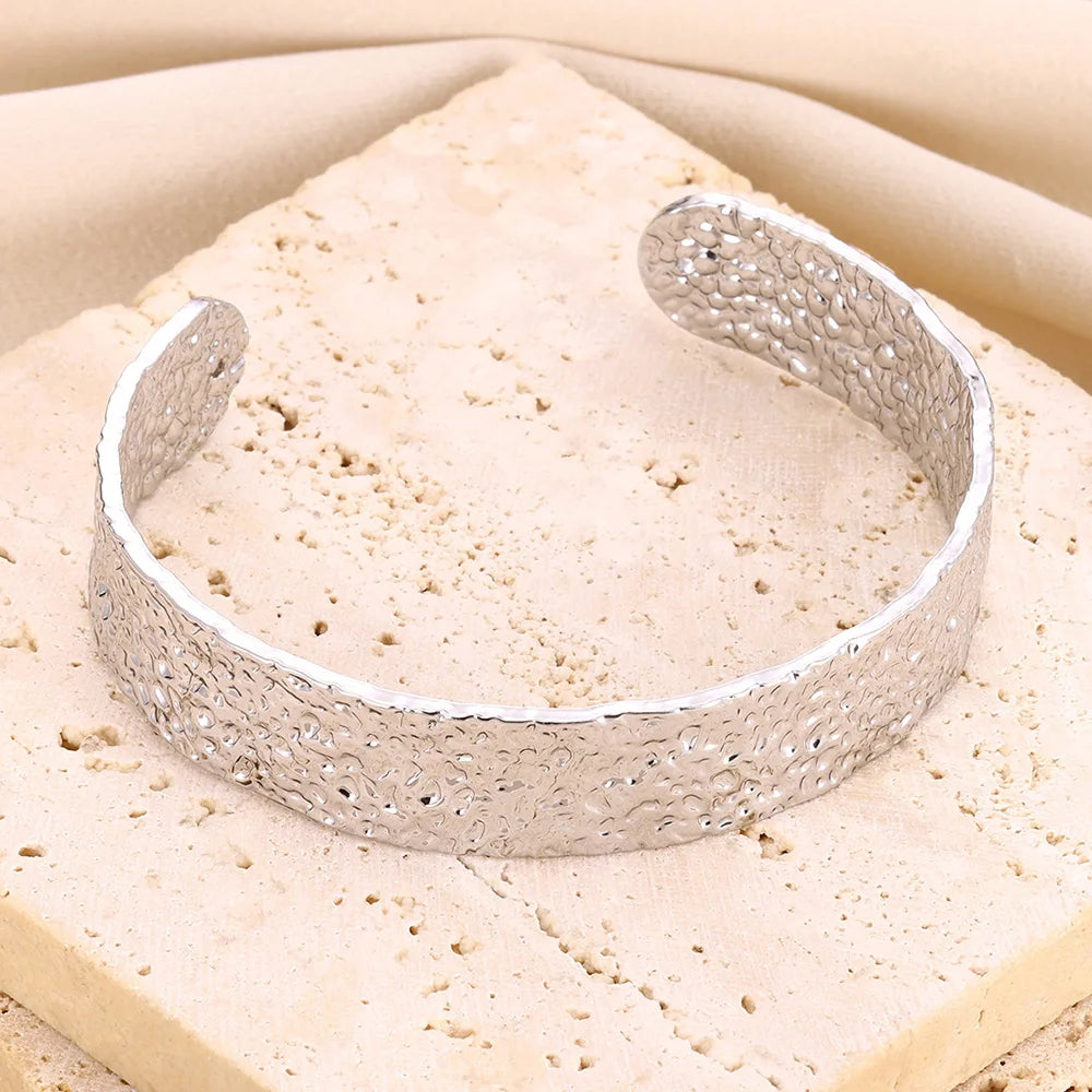 Bracelet manchette fin argenté pour femme, design irrégulier et finition brillante en acier inoxydable.