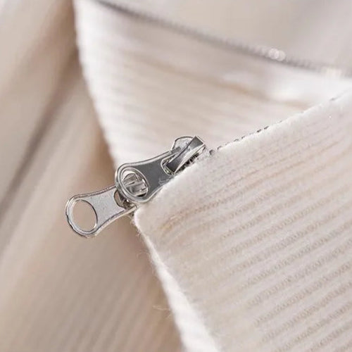 Détail de la fermeture éclair du cardigan beige DORIAN, permettant un ajustement facile du col. Un design simple et élégant qui assure à la fois confort et fonctionnalité.