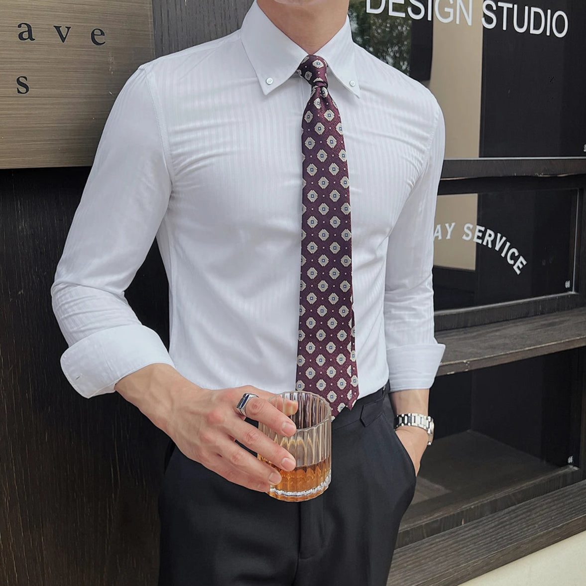 Chemise slim blanche à rayures portée avec une montre élégante et une ceinture en cuir, renforçant un look sophistiqué et distingué.