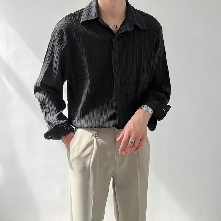 Gros plan sur le tissu plissé noir de la chemise, texture subtile et sophistiquée, idéale pour une tenue formelle