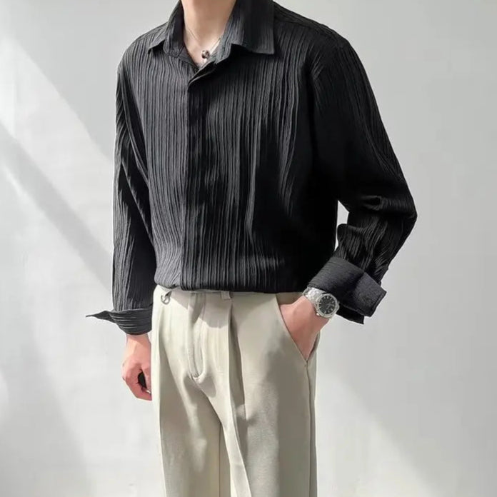 Chemise plissée noire idéale portée sous un blazer, tenue élégante et moderne pour homme.