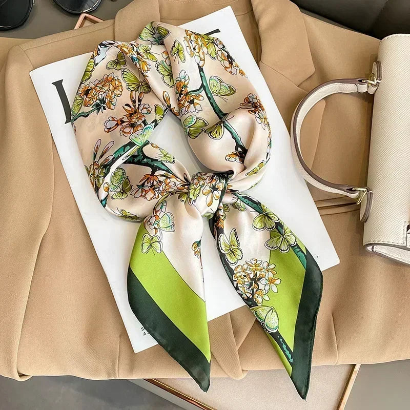 Zoom sur le foulard et ses motifs papillons élégants sur fond crème et nuances de vert clair et vert foncé.