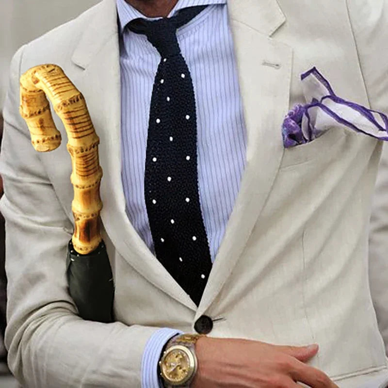 Homme habillé avec élégance, tenant un parapluie vert en bambou, accessoire chic et luxueux, look old money