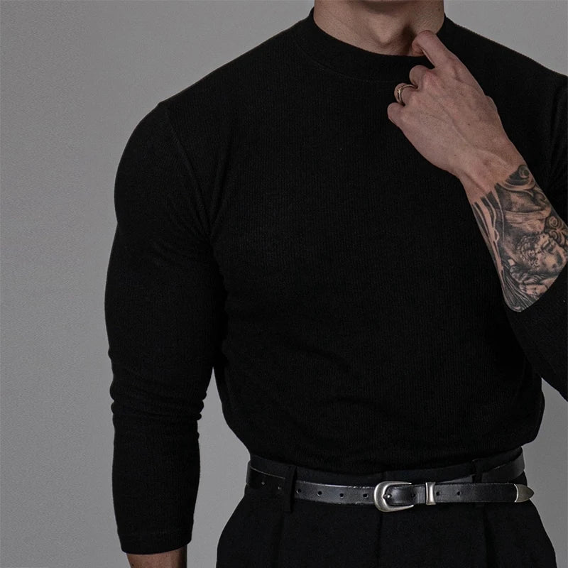 Homme portant le pull EZEKIEL noir en tricot côtelé fin, coupe ajustée et col montant, pour un style sobre et sophistiqué.