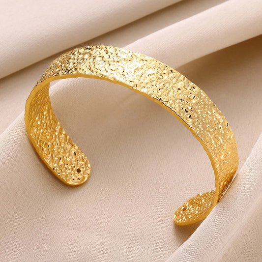 Zoom sur le design texturé du bracelet doré, manchette ouverte au style audacieux et élégant.