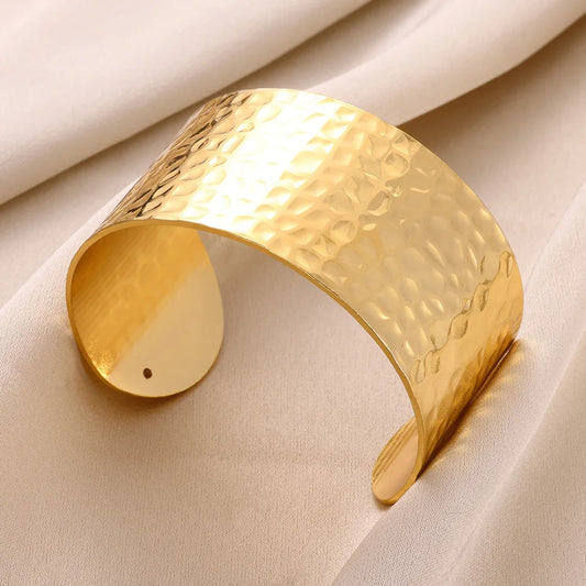 Zoom sur le design texturé du bracelet doré, manchette ouverte au style audacieux et élégant.