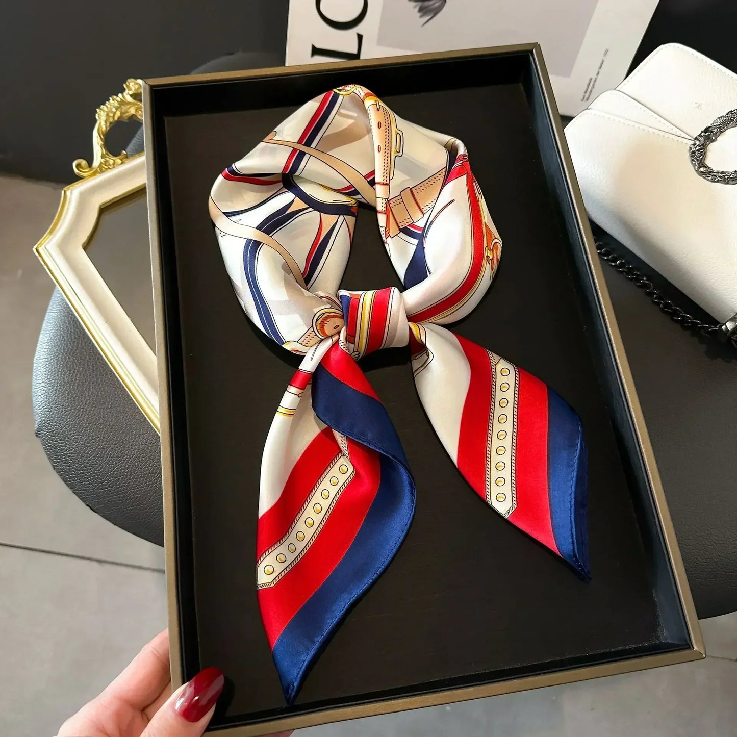 Foulard carré bleu marine, rouge et blanc cassé à plat sur fond neutre.