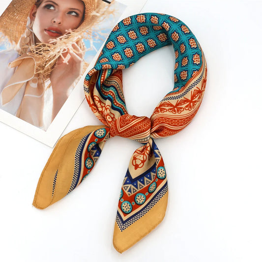 Foulard carré orange, bleu et doré sur fond blanc.