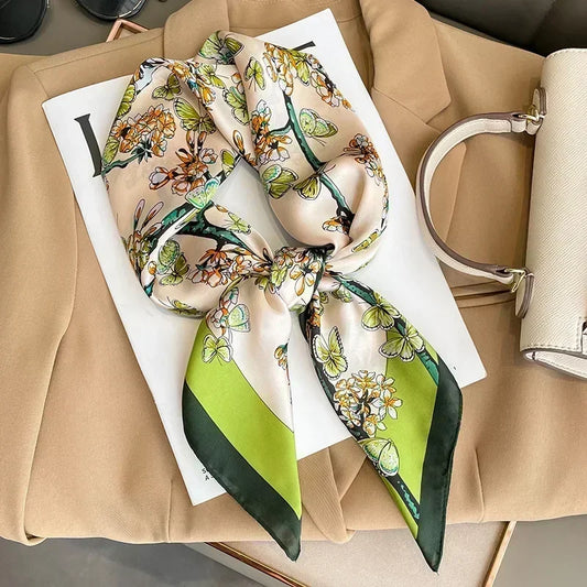 Zoom sur le foulard et ses motifs papillons élégants sur fond crème et nuances de vert clair et vert foncé.