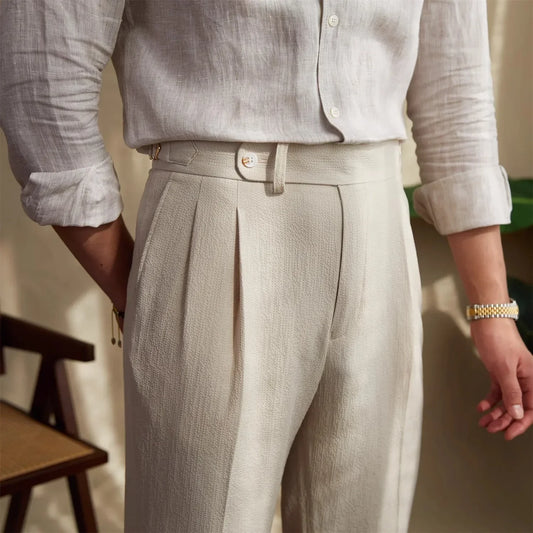 Pantalon ASHBURY beige, vue de demi-profil. Ceinture boutonnée et ajusteurs latéraux pour un maintien sur mesure. Alliance parfaite entre modernité et héritage tailleur.