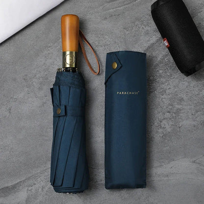 Zoom sur le parapluie bleu marine trois volets, avec manche en bois et tissu pongé doux, offrant une protection parfaite contre le vent et la pluie, rangement facile. 